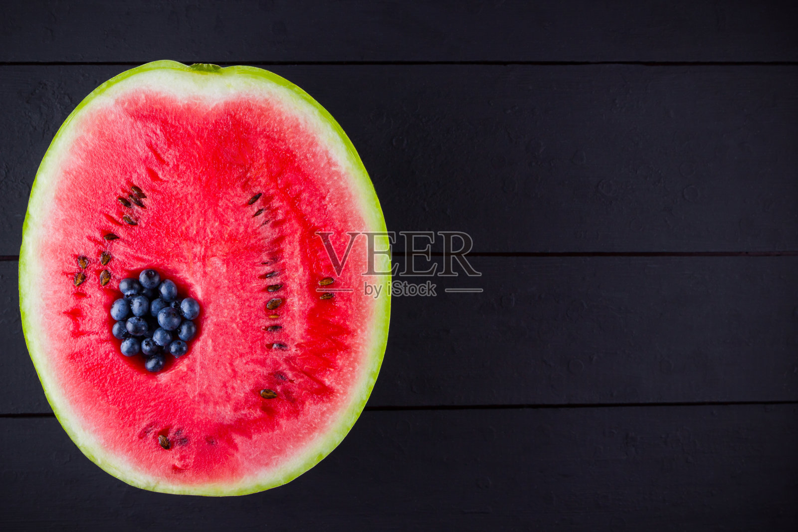 西瓜和蓝莓的深色背景。蓝莓在西瓜。创新食品的概念。俯视图照片摄影图片