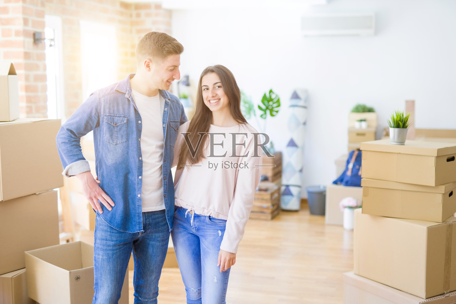 美丽的年轻夫妇拥抱在爱和黑板搬到一个新的家，微笑着为新公寓高兴照片摄影图片