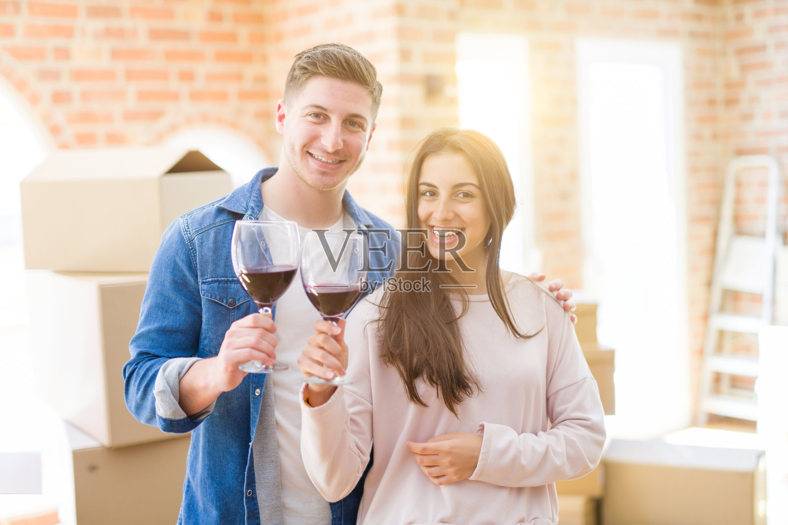 年轻美丽的夫妇喝一杯酒庆祝搬到新房子照片摄影图片