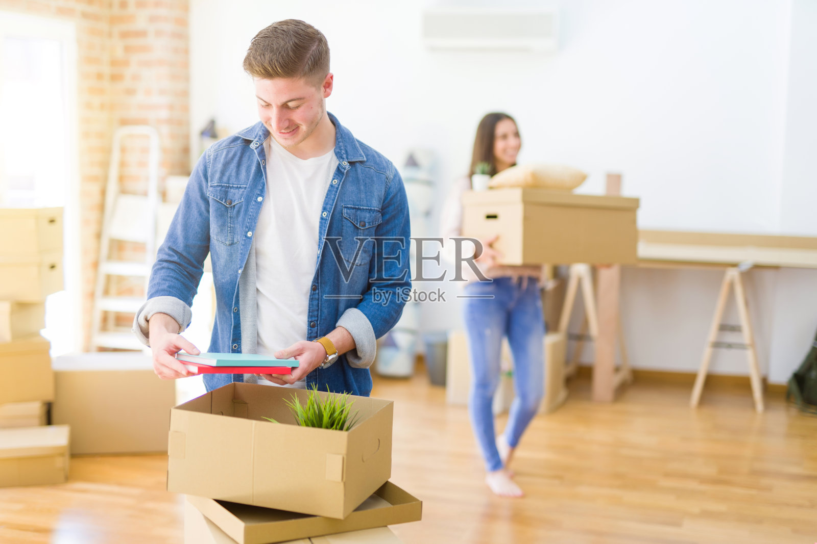 一对美丽的年轻夫妇搬到新家，对新公寓感到兴奋照片摄影图片