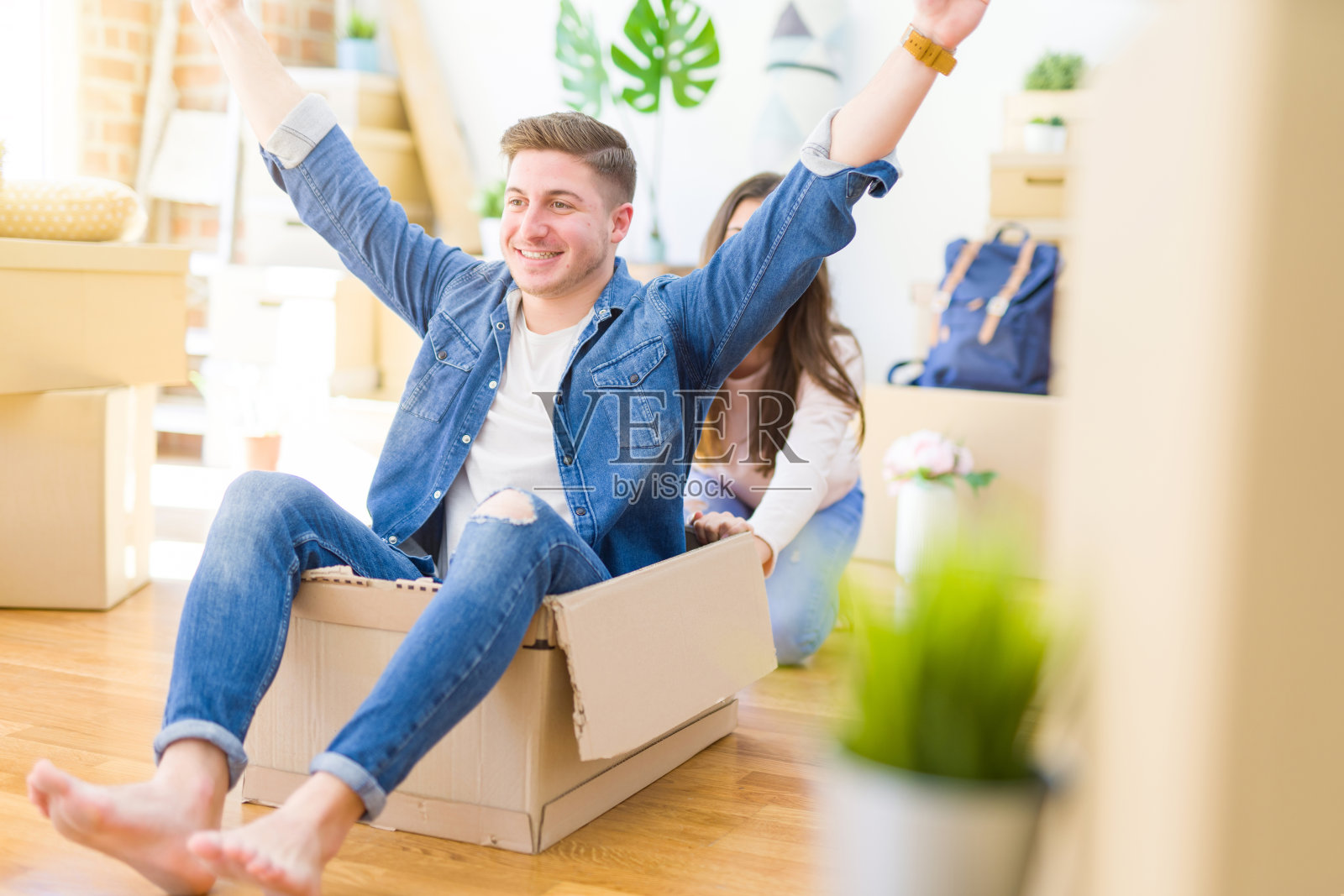 美丽的年轻夫妇笑在爱有乐趣骑在一个纸箱里，庆祝搬到一个新的家照片摄影图片