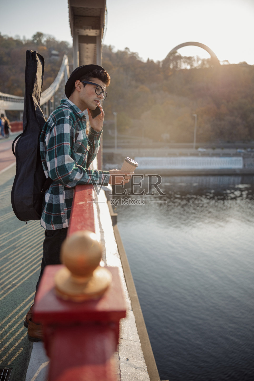 戴着眼镜，戴着帽子的年轻人在弹吉他照片摄影图片