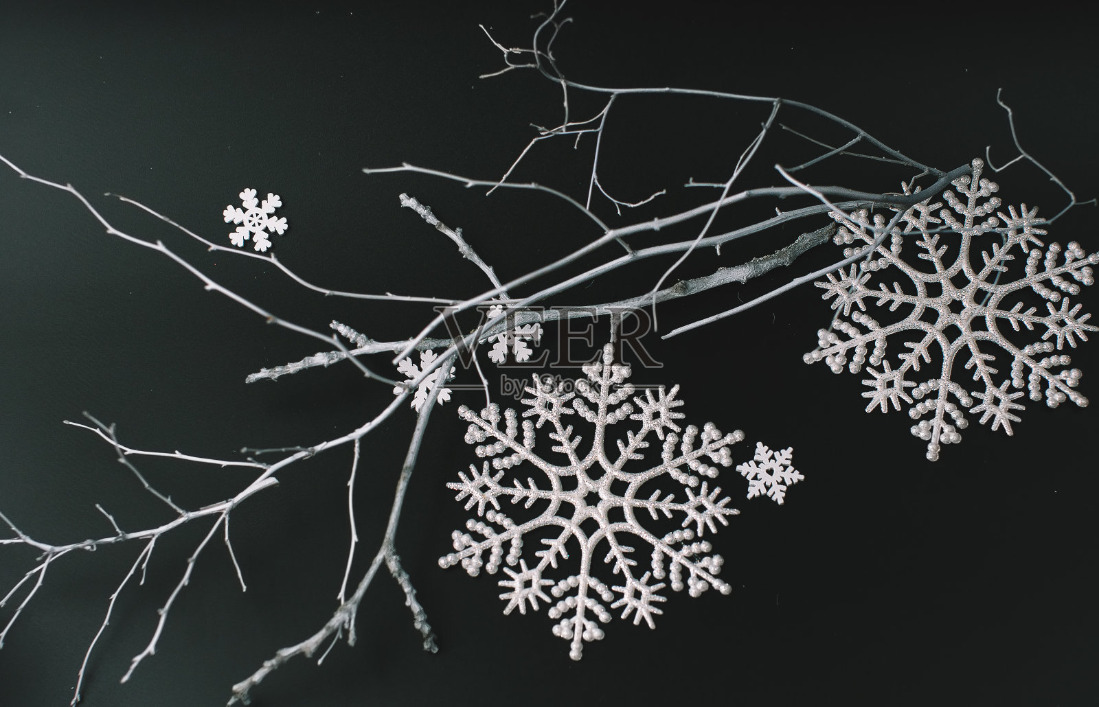 黑色的圣诞背景与白色物体形成鲜明的对比——自然绘制的白色树枝，雪花，圣诞玩具，银色包装的礼物照片摄影图片