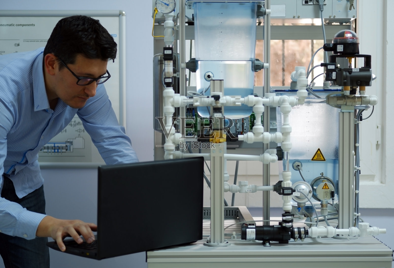 专注于用笔记本电脑为模拟工艺套件编写PLC程序的工程师。工业4.0车间在自动化教育中心。工程师正在学习如何给PLC编程。照片摄影图片