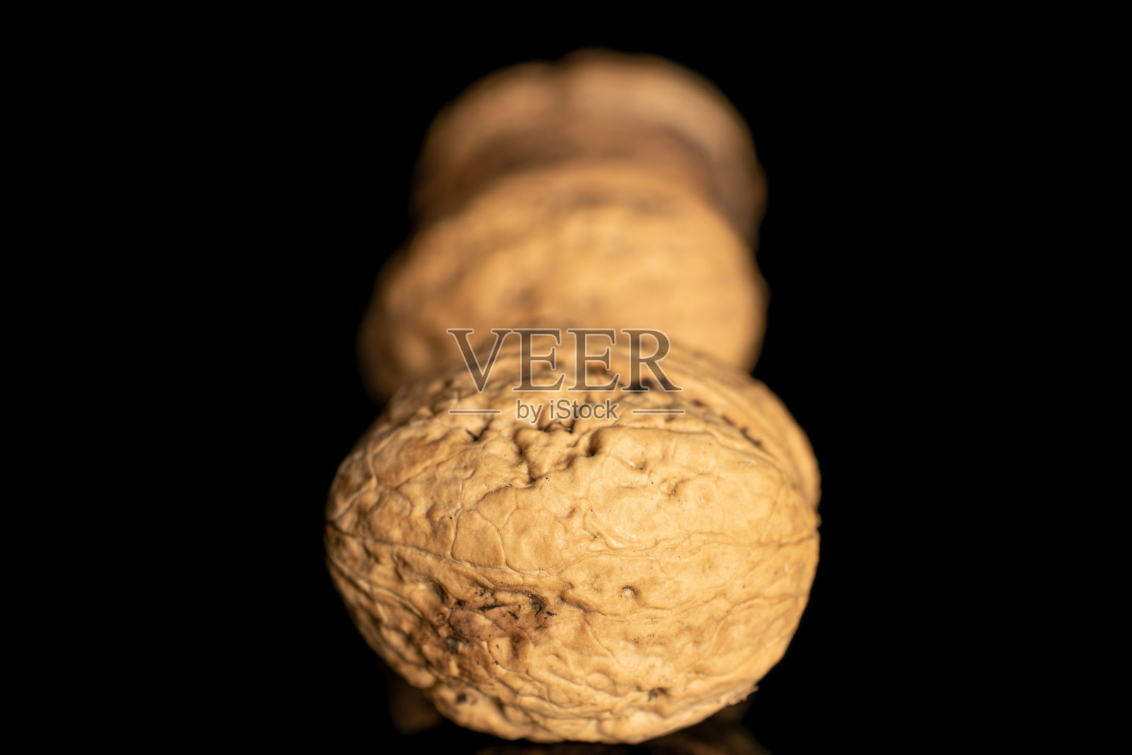 新鲜的棕色胡桃孤立在黑色玻璃上照片摄影图片