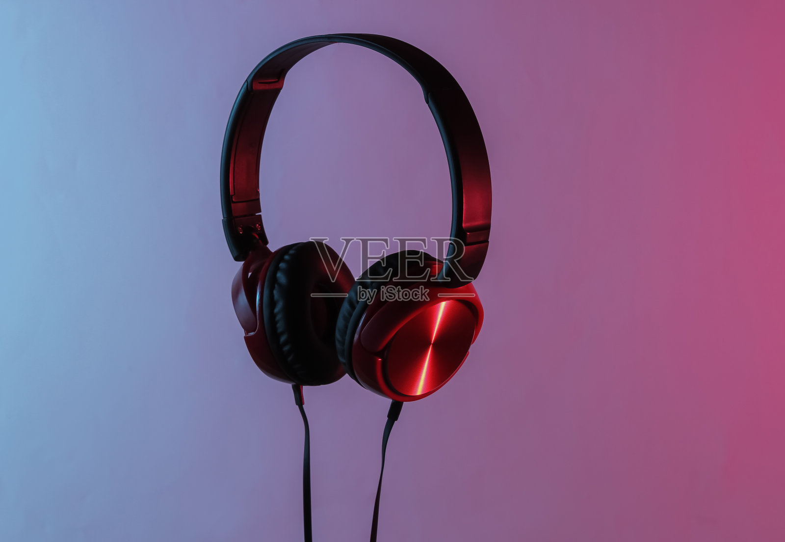 带电缆的新耳机。极简的耳机照片。黑红dj耳机。霓虹蓝红渐变光。复古浪潮，80年代流行文化照片摄影图片