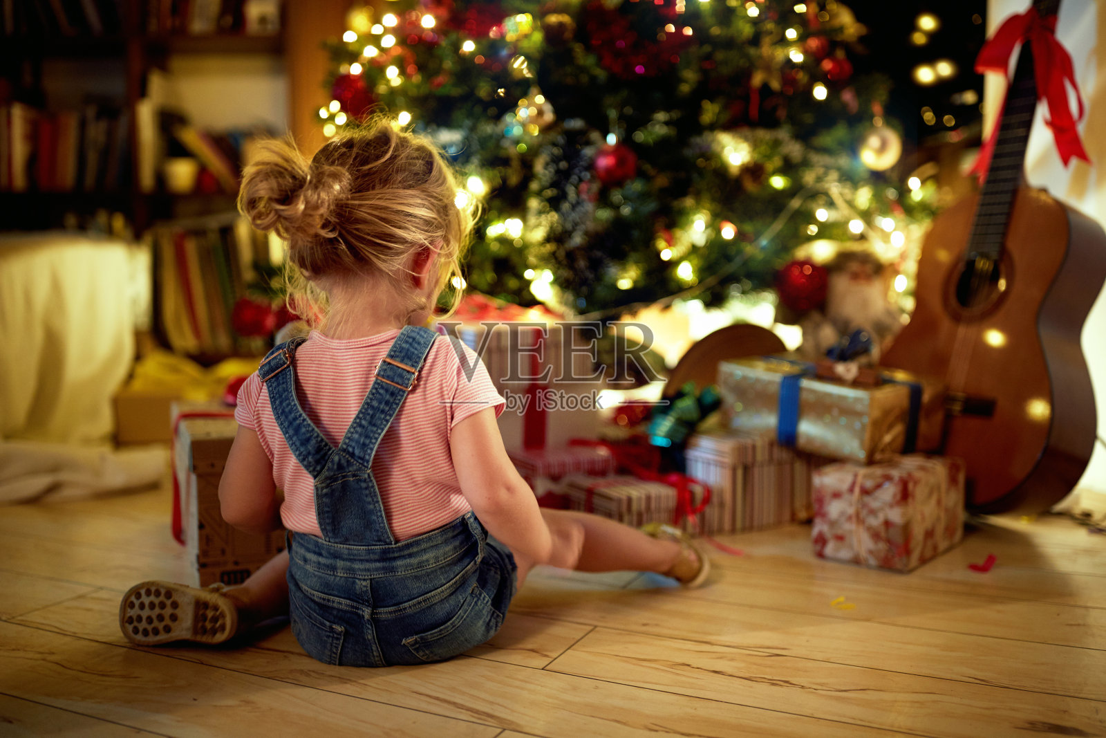 快乐的女孩打开圣诞礼物。圣诞魔法在家。照片摄影图片