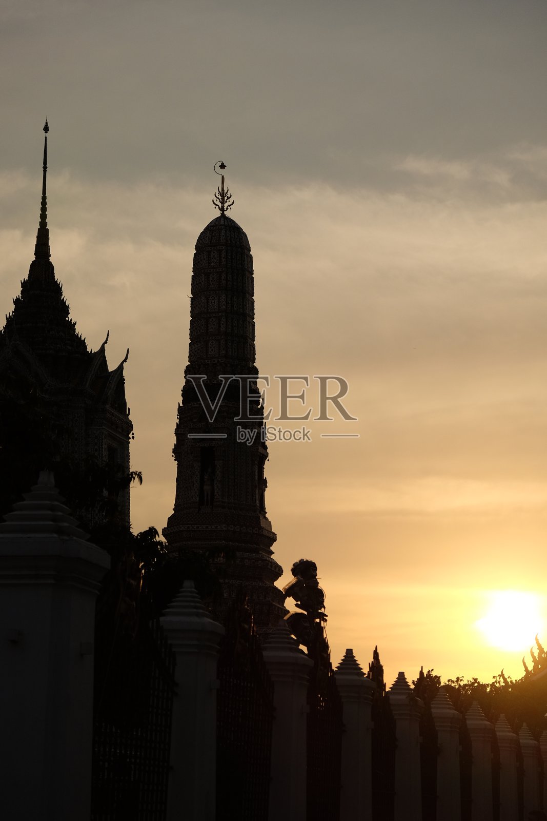 在日落天空的背景下，Wat Arun temple的塔的剪影。照片摄影图片