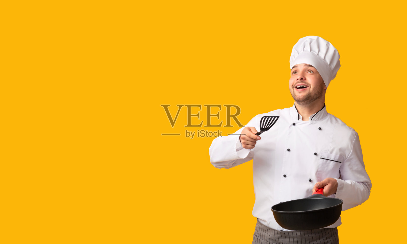 厨师拿着平底锅，扔着看不见的食物站在摄影棚拍摄照片摄影图片