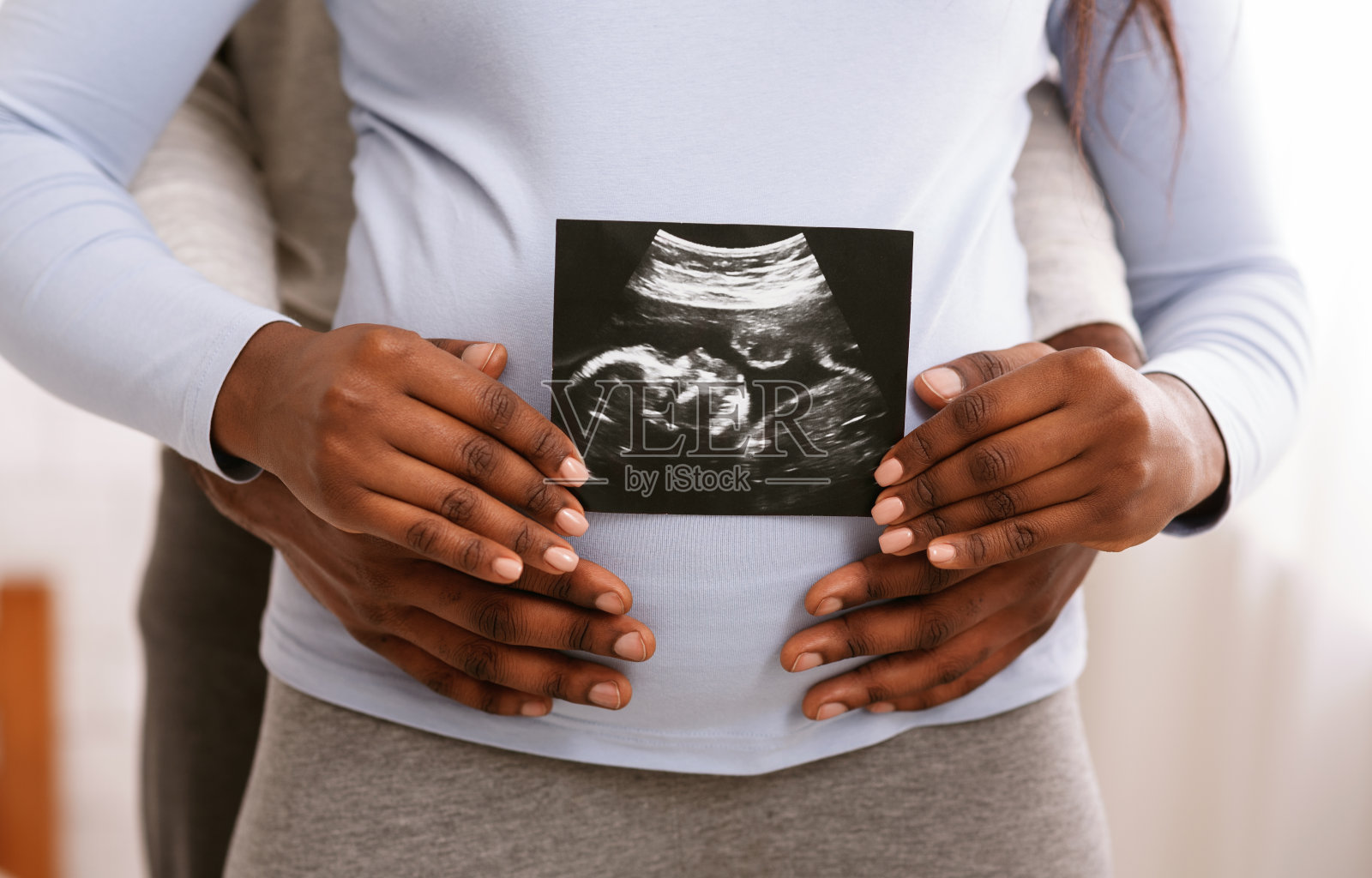 一对黑人夫妇在女人的肚子前拿着超声波图像照片摄影图片