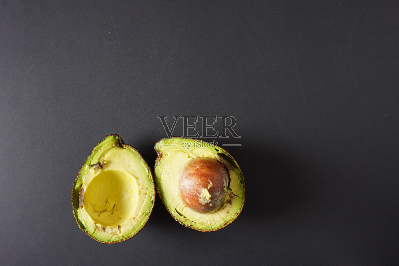 黑色背景上放着两张不完美的牛油果皮照片摄影图片