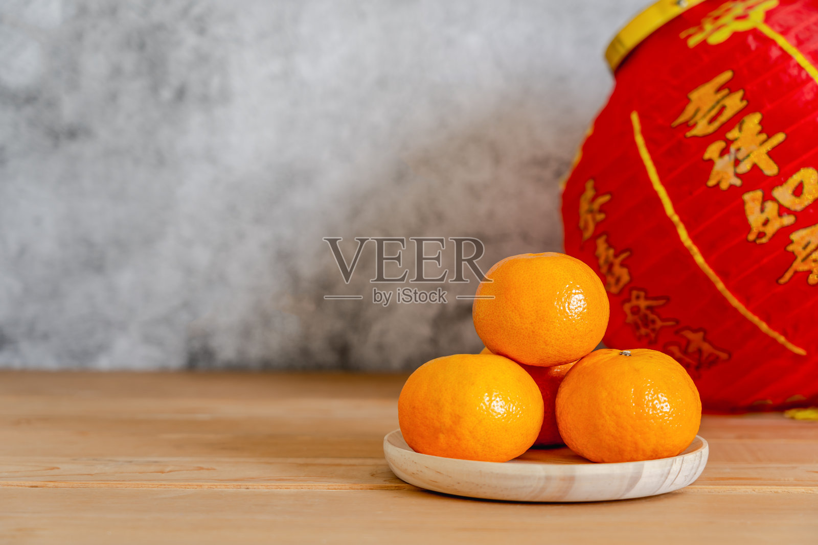 农历新年的配件和中国新年假期概念假日背景。橙色木篮子和红色灯笼在现代乡村棕色木制和灰色的石头背景。空间的文本。照片摄影图片