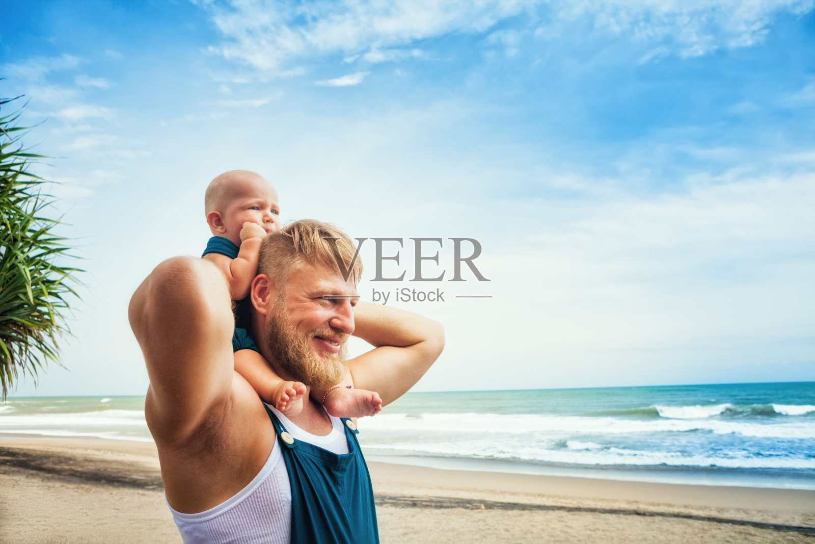 年轻的胡子父亲，有趣的儿子走过热带海滩照片摄影图片