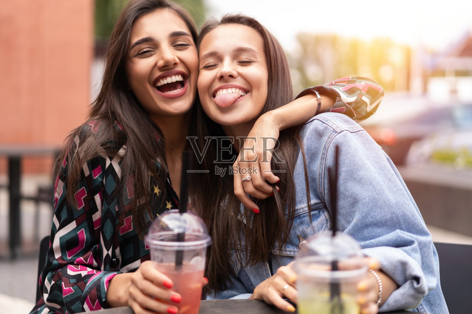 时髦的女朋友在城市背景下喝鸡尾酒照片摄影图片