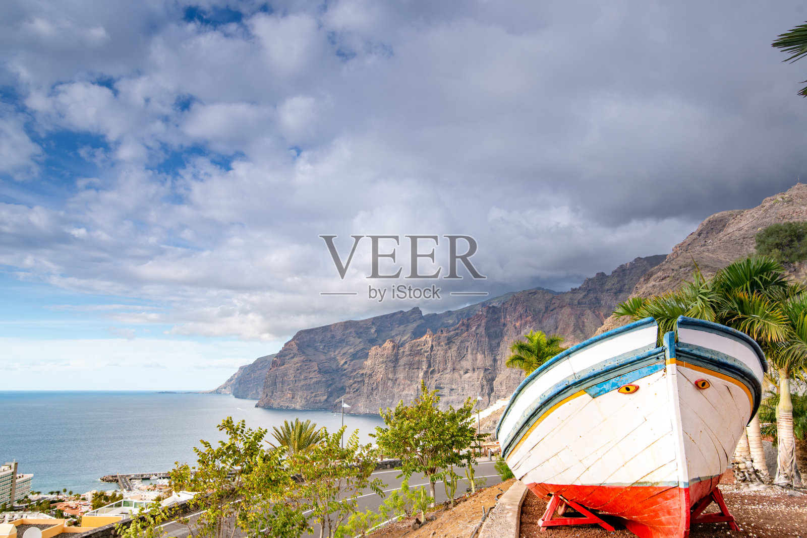 充满活力的水平景观与城市景观与陡峭的悬崖和阴天与在前景的船，Acantilados de Los Gigantes，波多黎各圣地亚哥，特内里费，加那利群岛，西班牙-库存照片照片摄影图片