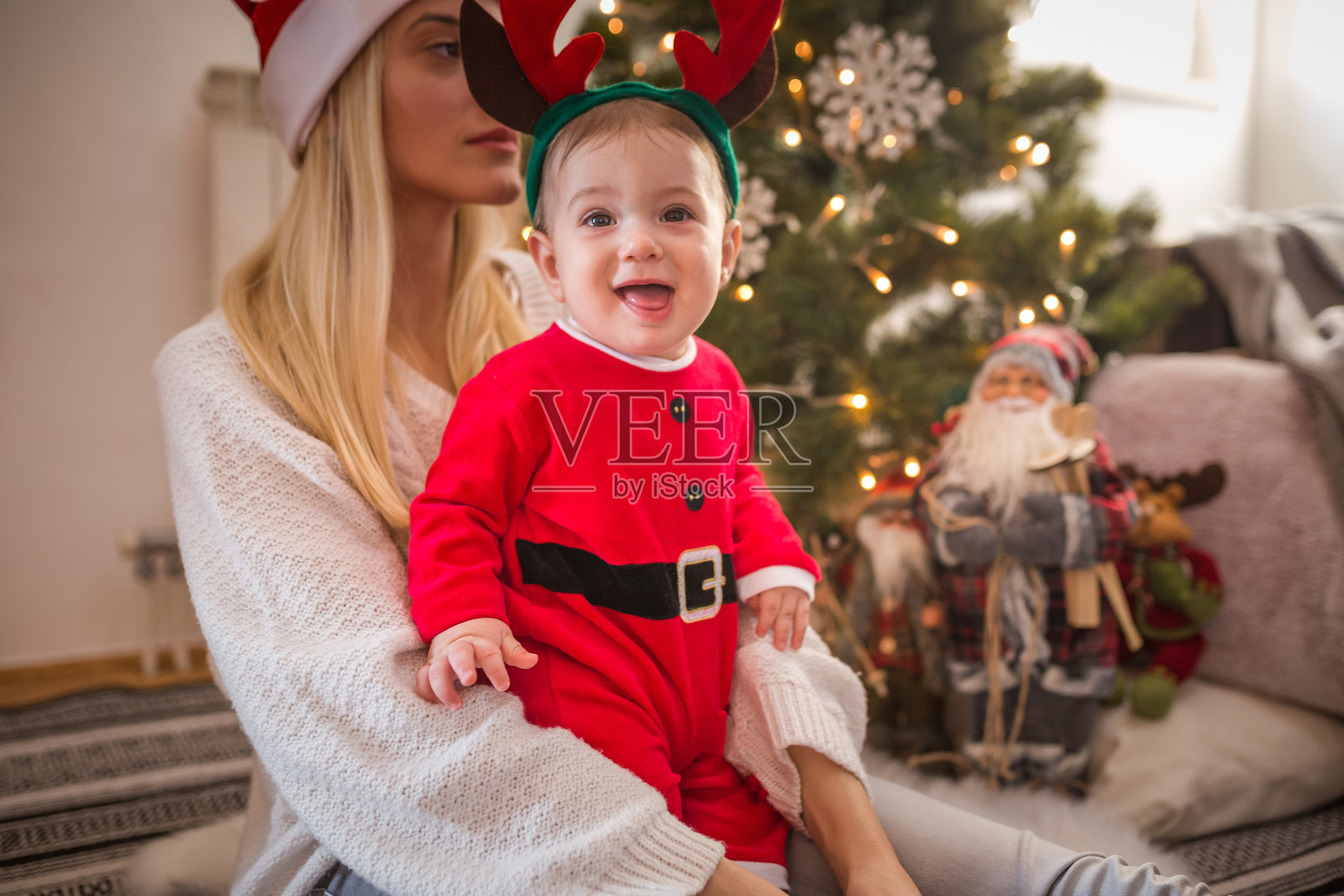一位年轻的母亲在圣诞树前和她的小儿子玩耍照片摄影图片
