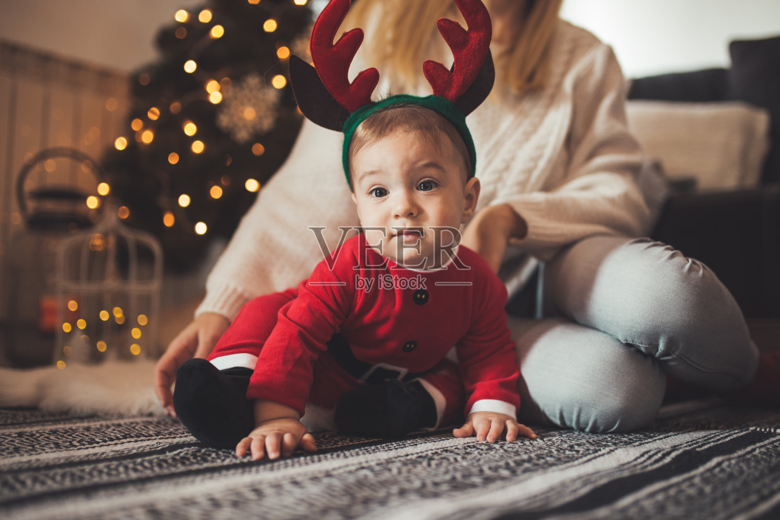 可爱的小男孩穿着圣诞老人的服装在圣诞树前摆姿势照片摄影图片