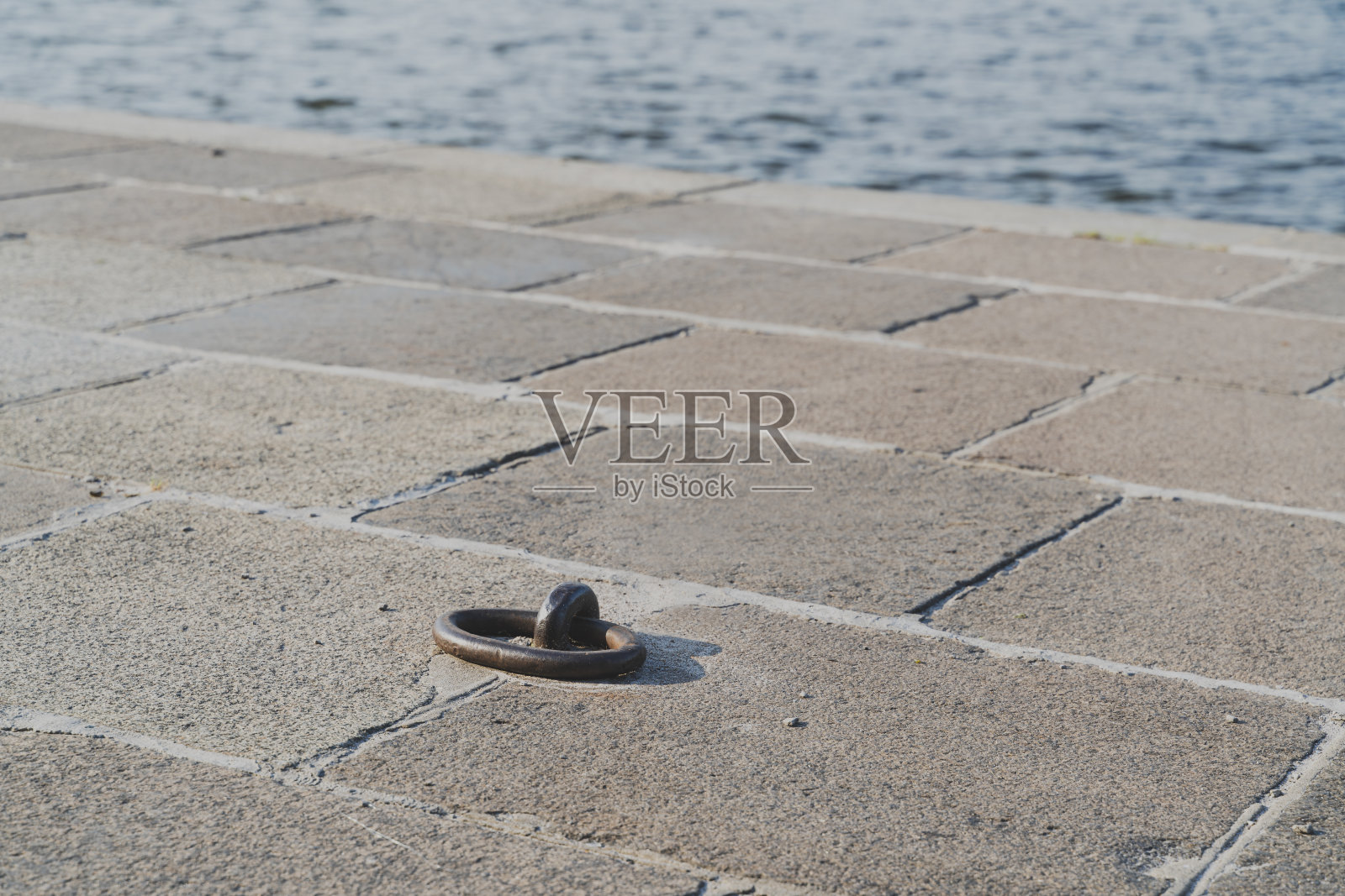 船系泊环在码头上，水在背景上照片摄影图片