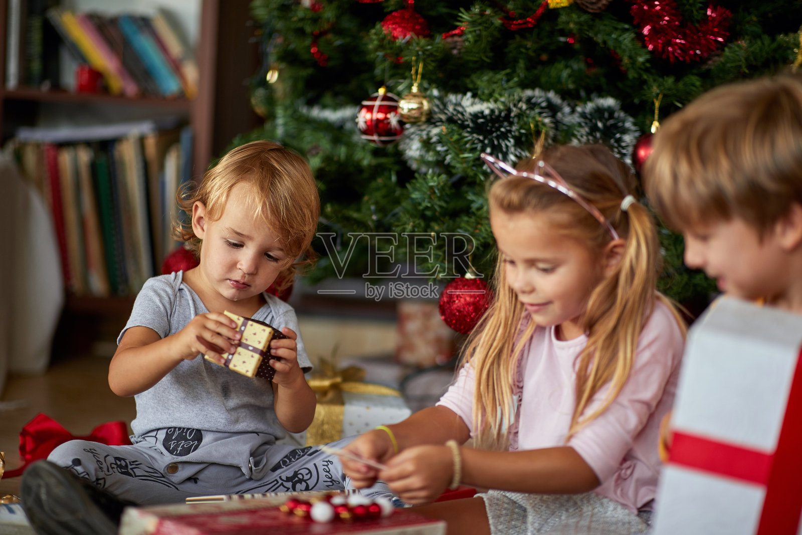 男孩打开圣诞礼物。惊讶的孩子们打开圣诞礼品盒照片摄影图片