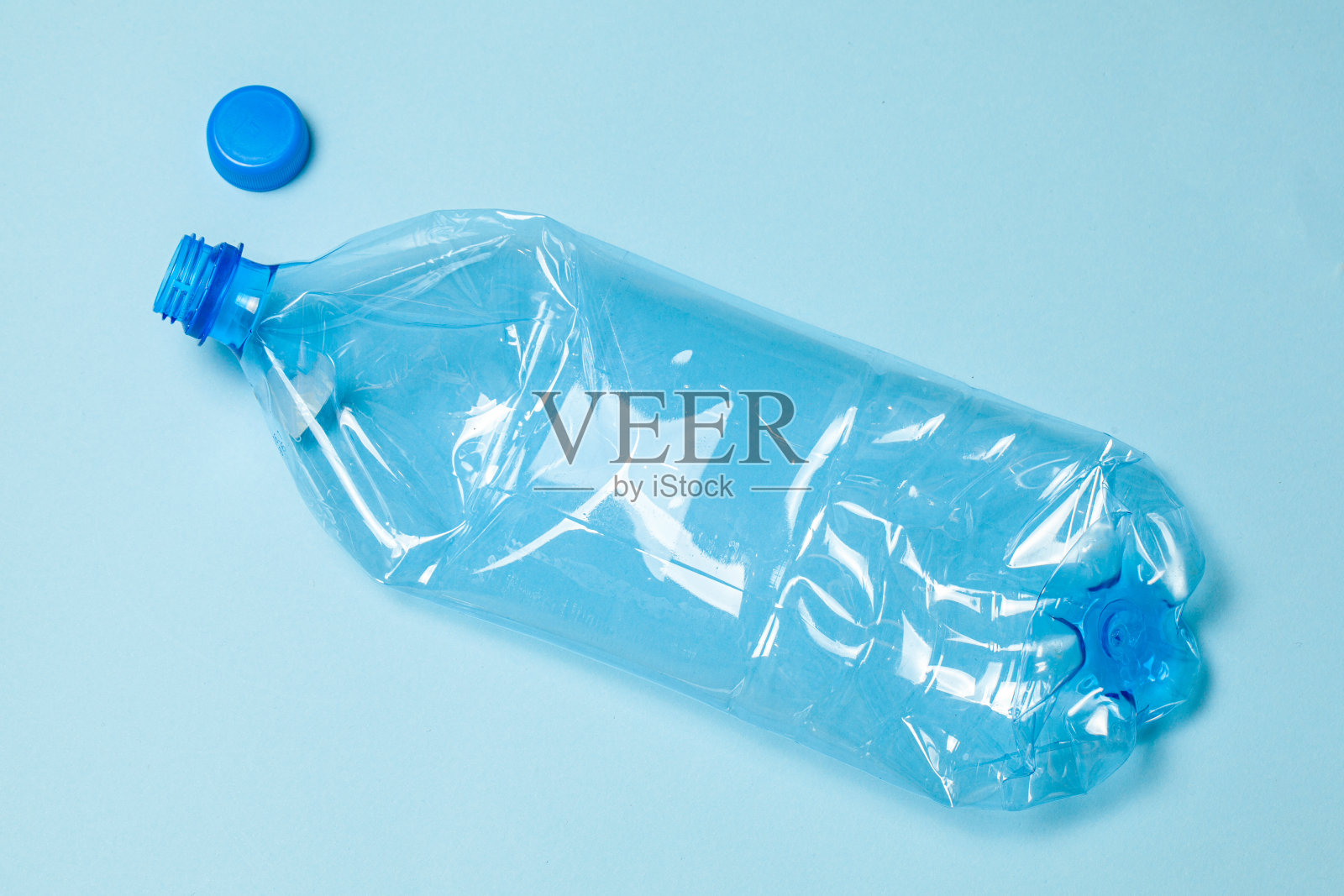 蓝色背景上的皱巴巴的塑料瓶。塑料垃圾照片摄影图片