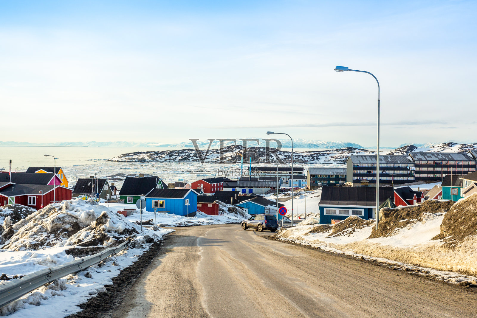 格陵兰岛阿凡纳塔市伊卢利萨特，北极圈城市中心的全景，色彩斑斓的因纽特人的房子在被雪覆盖的岩石山上，背景是山脉照片摄影图片