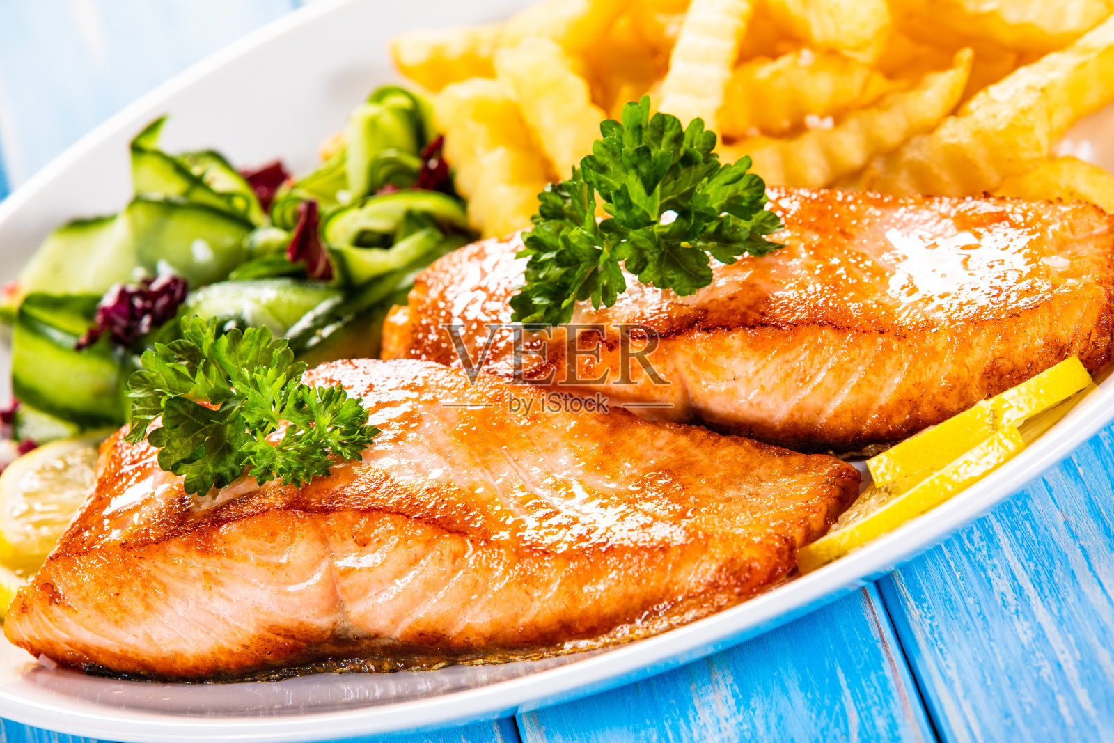 木制背景上的烧烤鲑鱼、炸薯条和蔬菜照片摄影图片