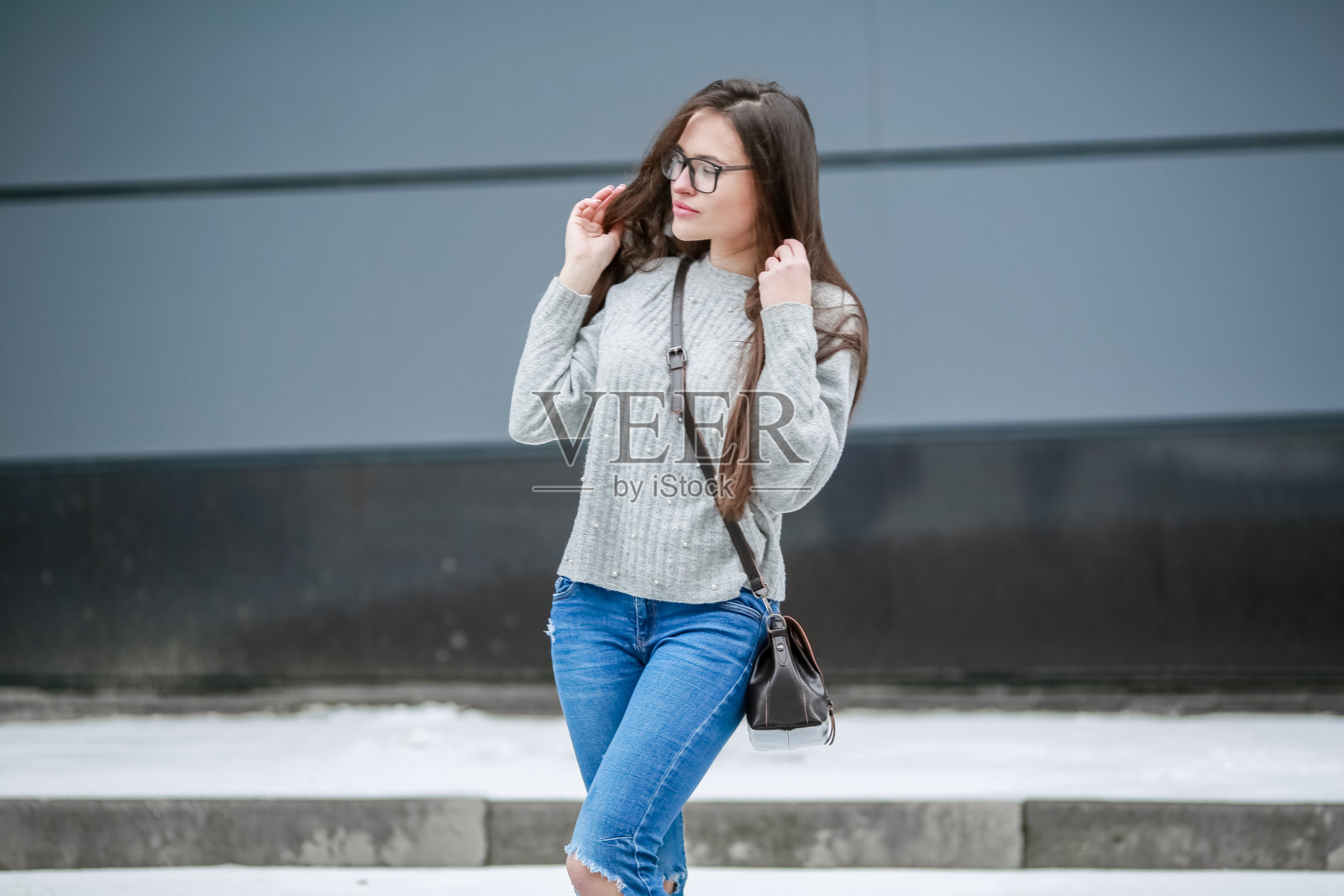 年轻漂亮的女人穿着一件时髦的手织毛衣独自站在街上照片摄影图片