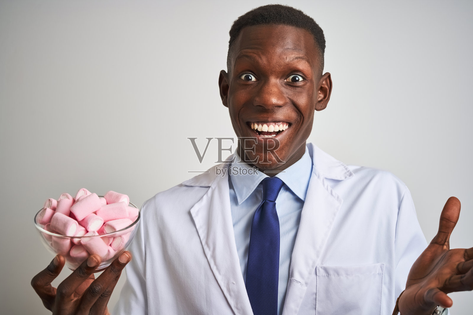 非裔美国医生男子拿着碗与棉花糖在孤立的白色背景非常高兴和兴奋，胜利者的表情庆祝胜利尖叫着大大的微笑和举起手照片摄影图片
