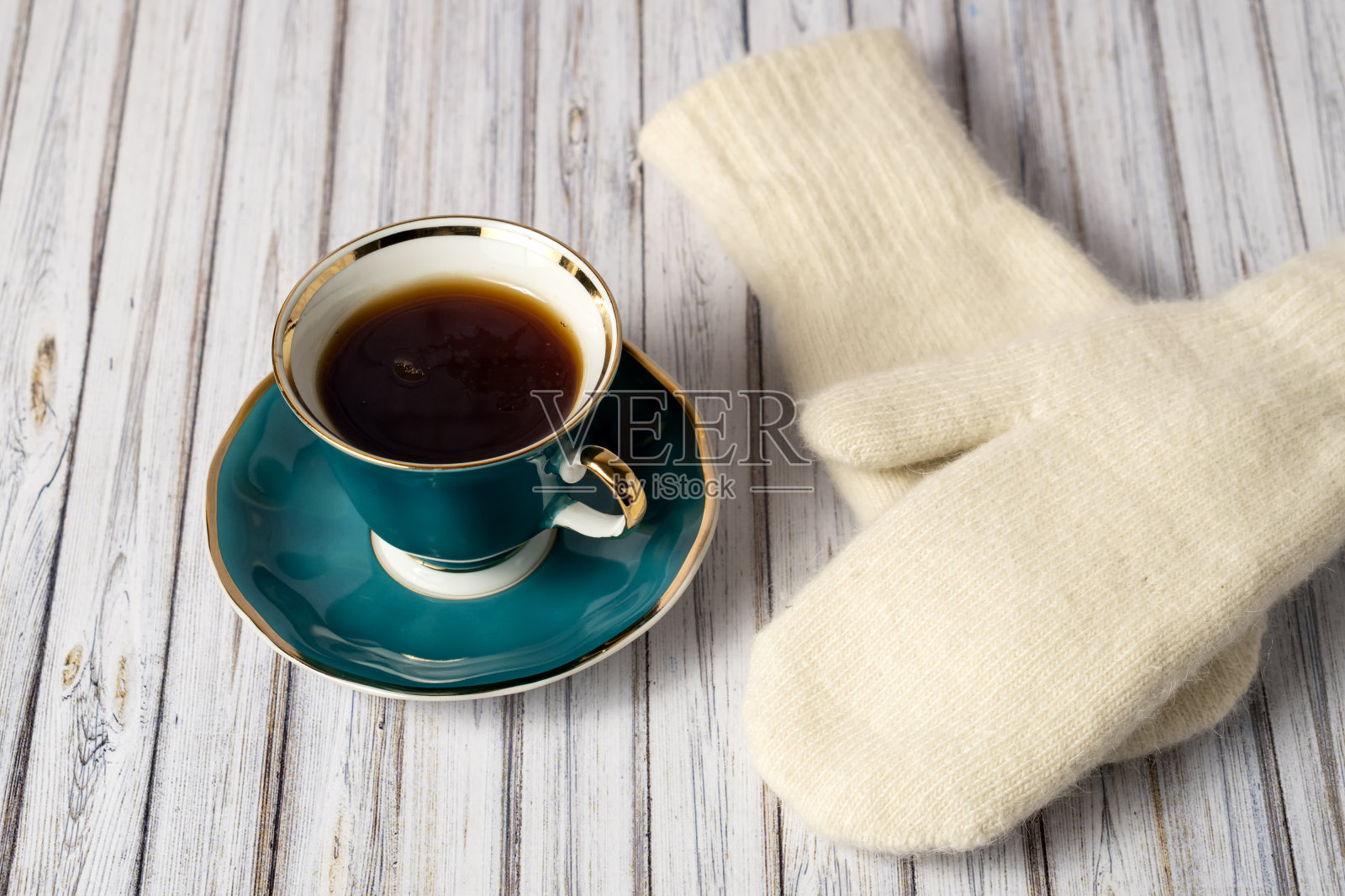 木桌上放着一杯热茶和一副白色手套照片摄影图片