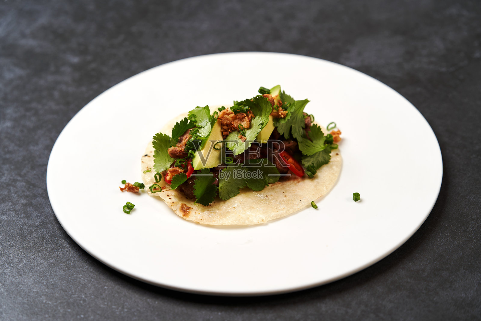 墨西哥玉米饼配牛肉，西红柿，鳄梨，辣椒和洋葱照片摄影图片