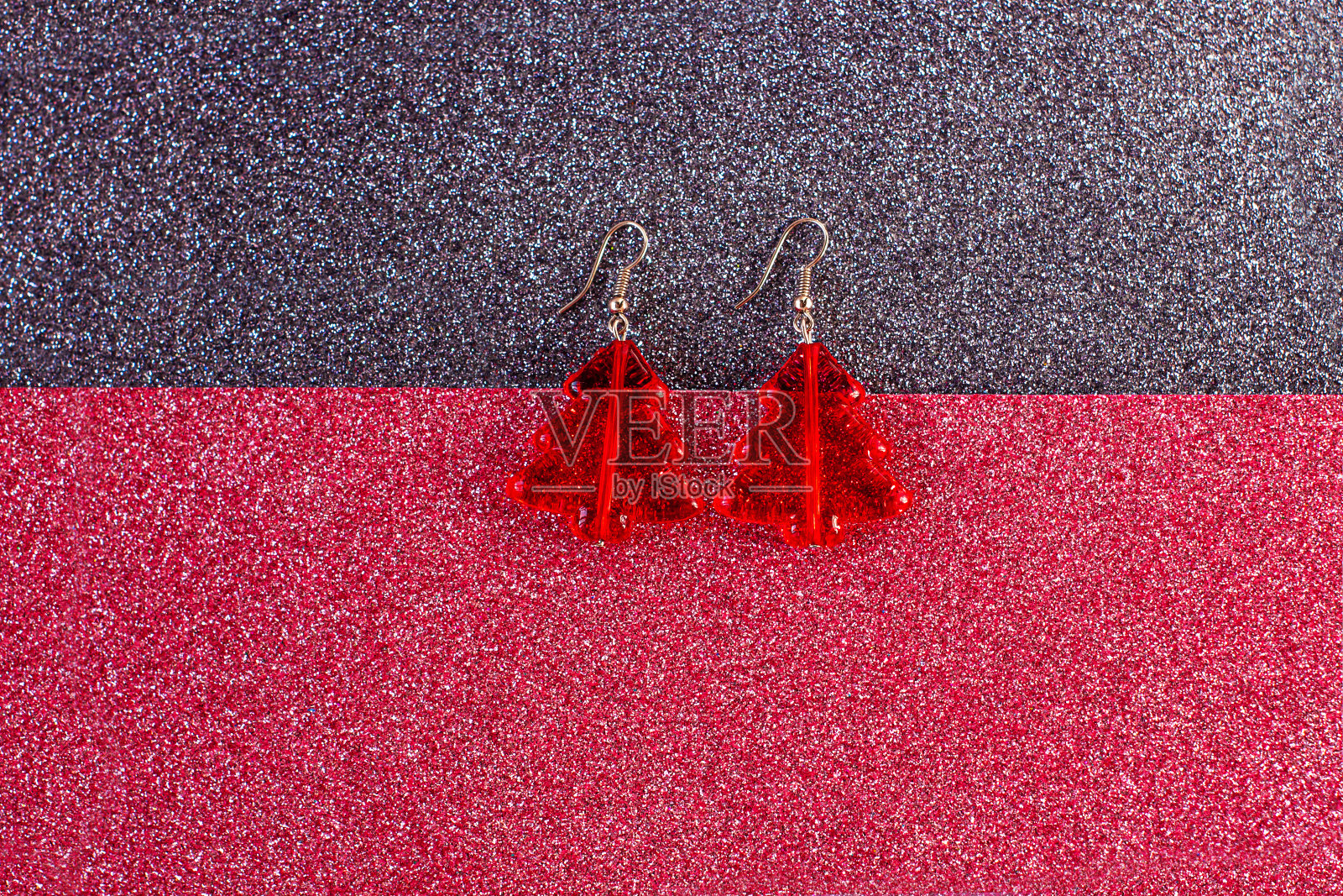 红色时髦的耳环，以圣诞树的形式，在黑色亮片的背景。最小的平面，假日的外观，横幅照片摄影图片