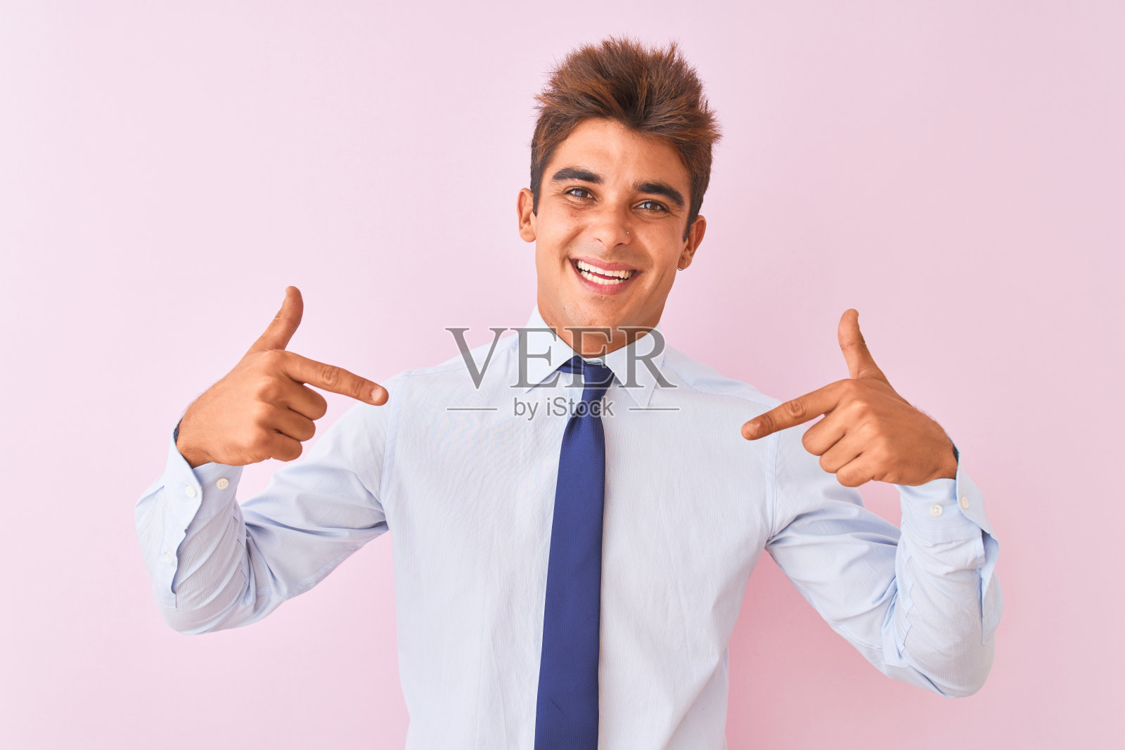 年轻英俊的商人穿着衬衫和领带站在孤立的粉红色背景看起来自信，脸上的微笑，用手指指着自己骄傲和幸福。照片摄影图片