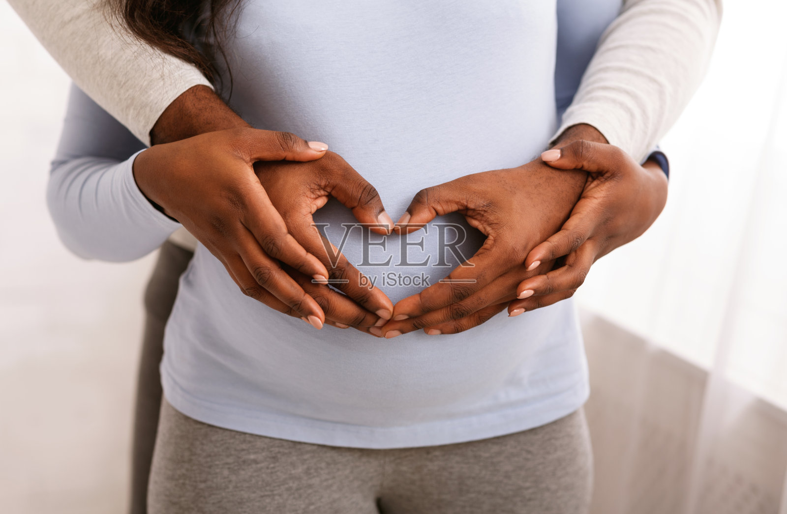 男人把手放在孕妇的肚子上呈心形照片摄影图片