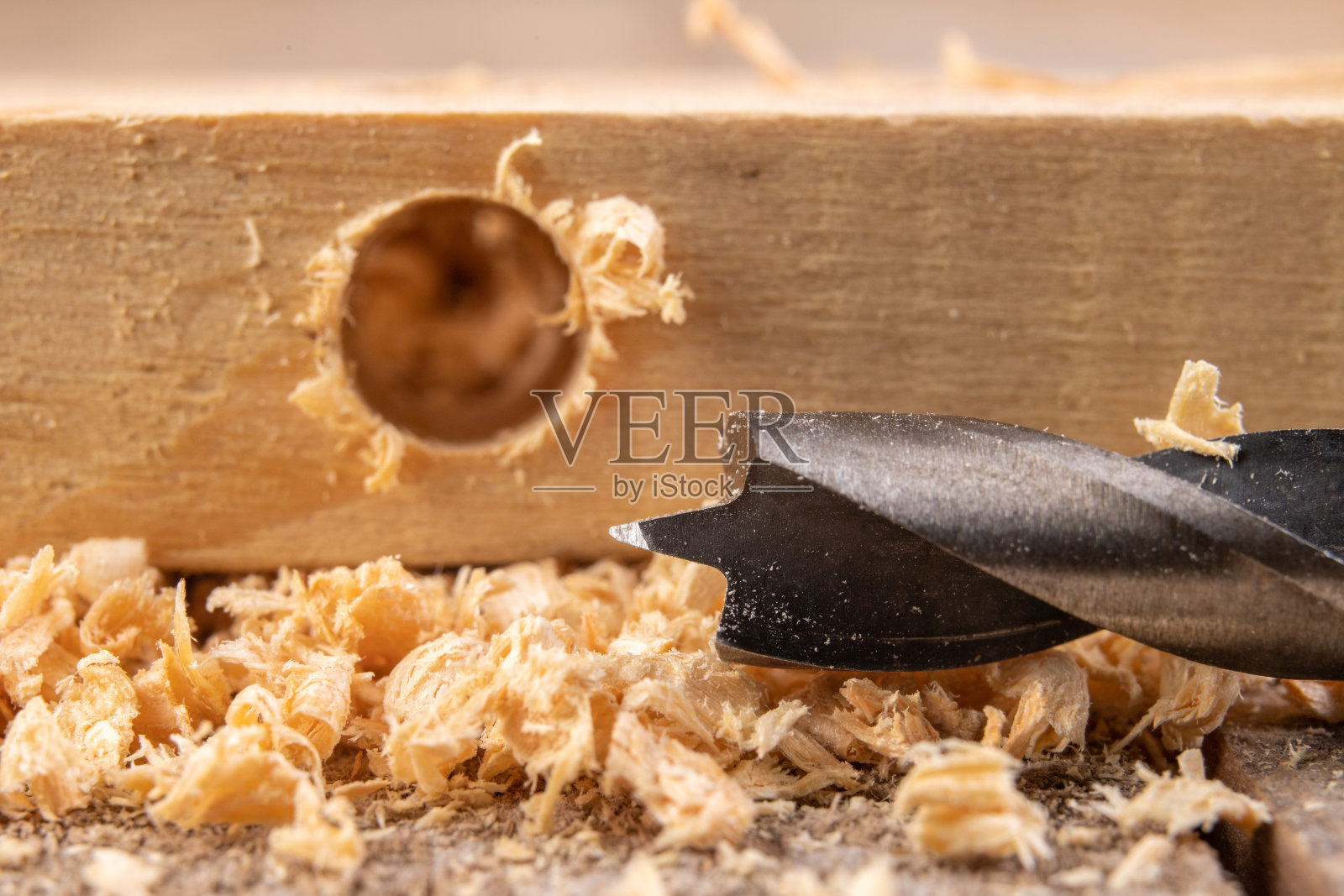 用钻头钻进木头。木工车间的小木工工作。黑暗的背景。照片摄影图片