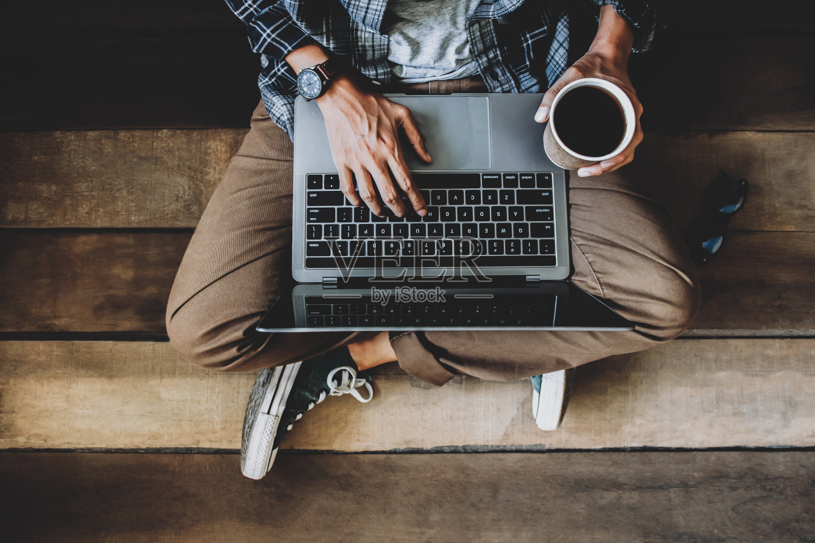 拿着咖啡杯坐在木地板上戴着眼镜用笔记本电脑在家里工作发送和回复电子邮件给客服照片摄影图片