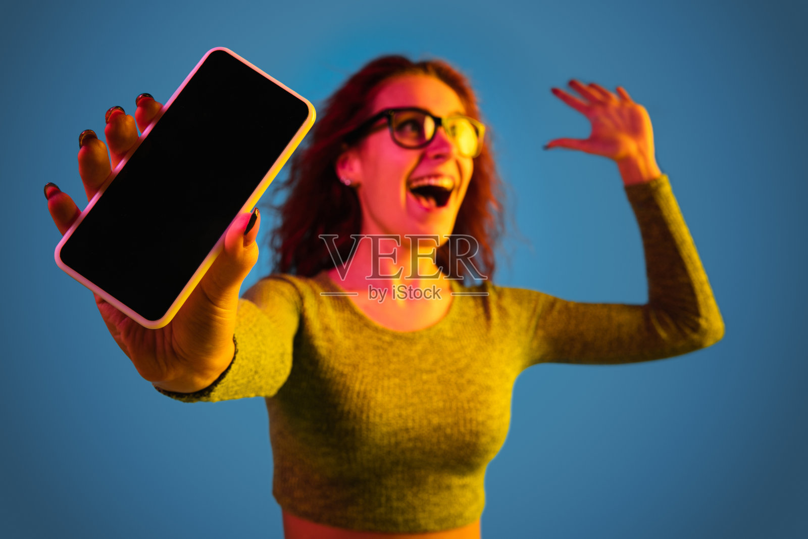 在霓虹灯下，一个白人妇女的肖像被隔离在蓝色的画室背景上照片摄影图片