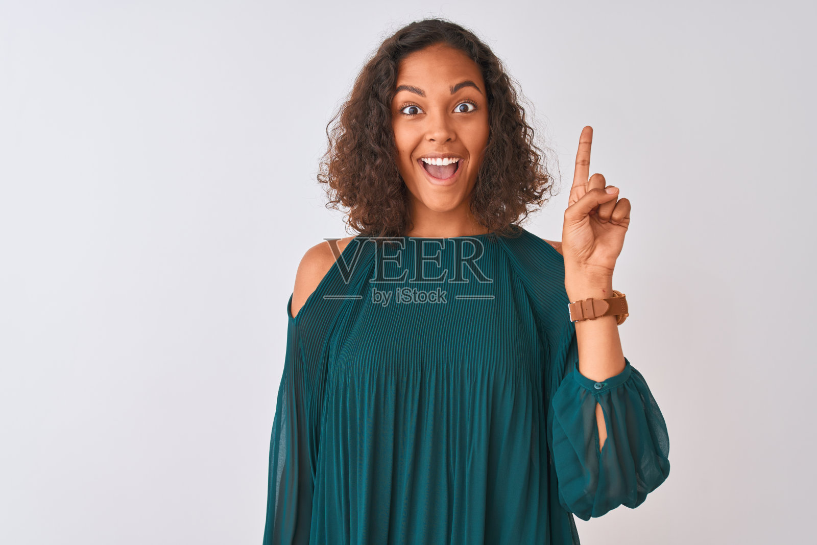 年轻的巴西女人穿着绿色t恤站在孤立的白色背景指向手指与成功的想法。退出和快乐。第一。照片摄影图片