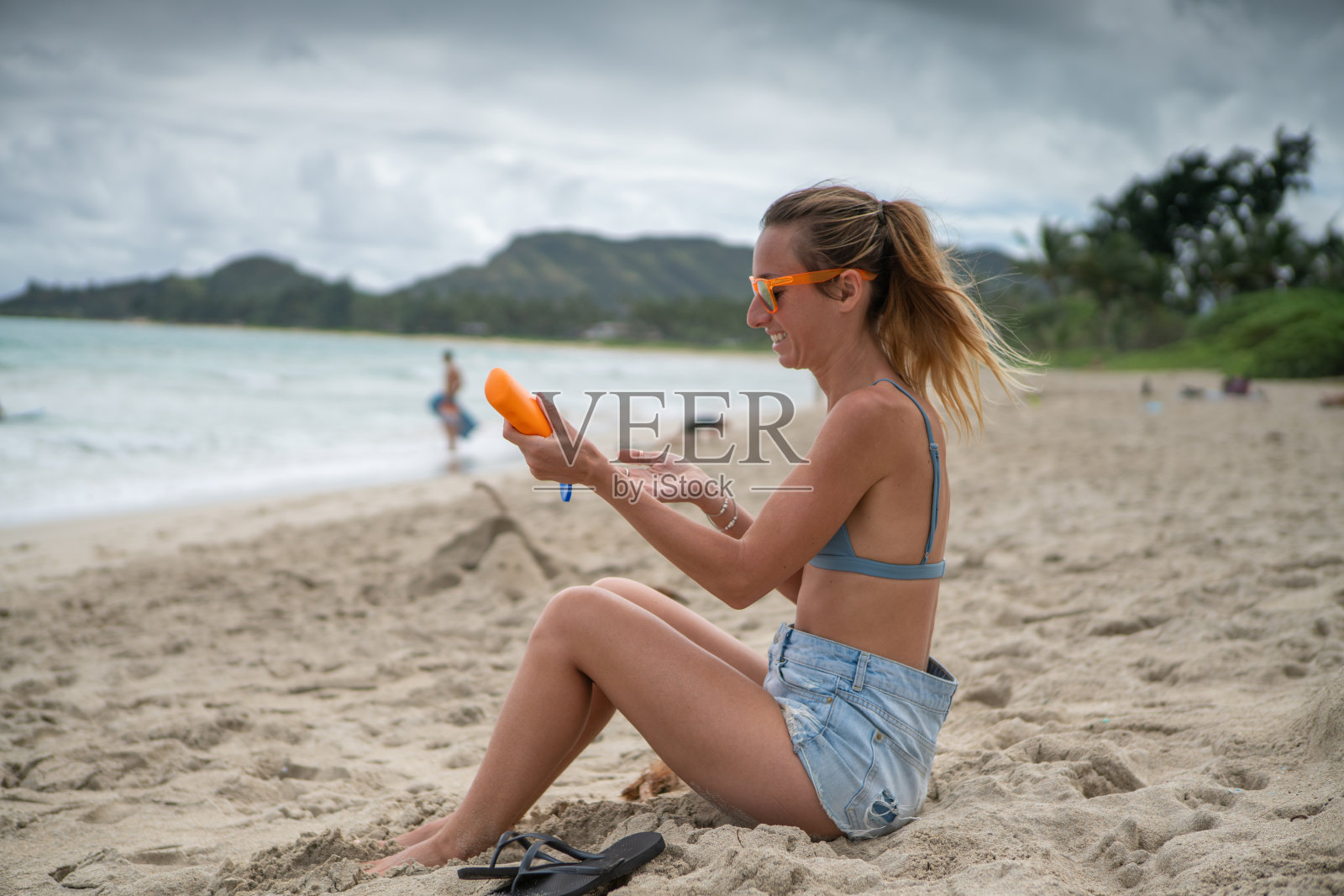 夏日——年轻女子在海滩上涂抹防晒霜，保护皮肤照片摄影图片