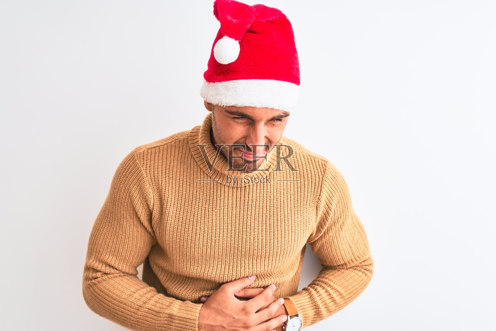 年轻英俊的男子穿着圣诞和高领毛衣过孤立的背景与手胃，因为恶心，痛苦的疾病感觉不舒服。疼痛的概念。照片摄影图片