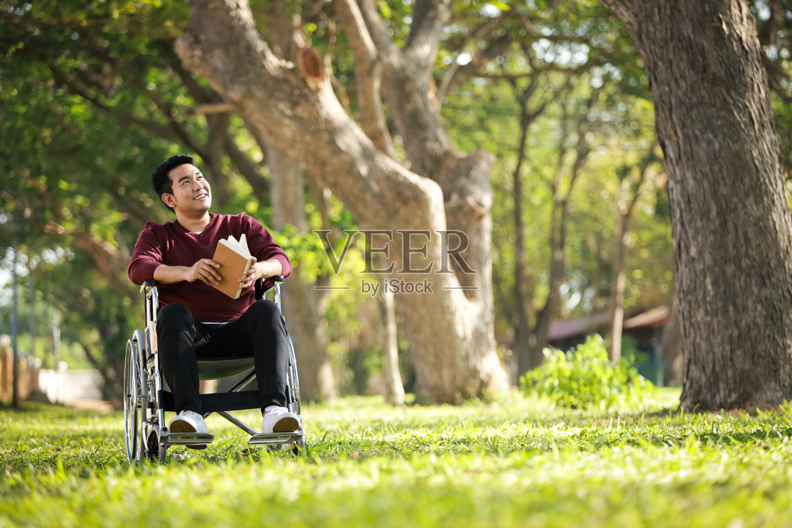 亚洲年轻人坐在轮椅上在公园医院照片摄影图片