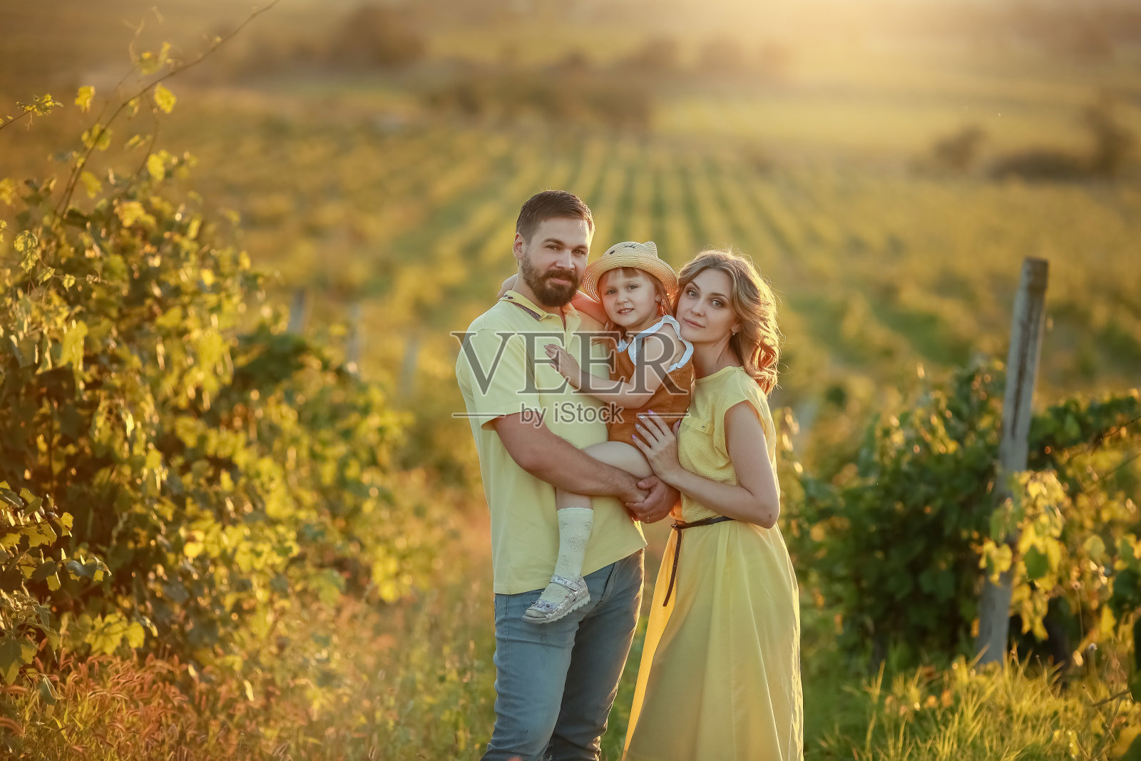 年轻的家庭和女儿走在草地在山的背景照片摄影图片