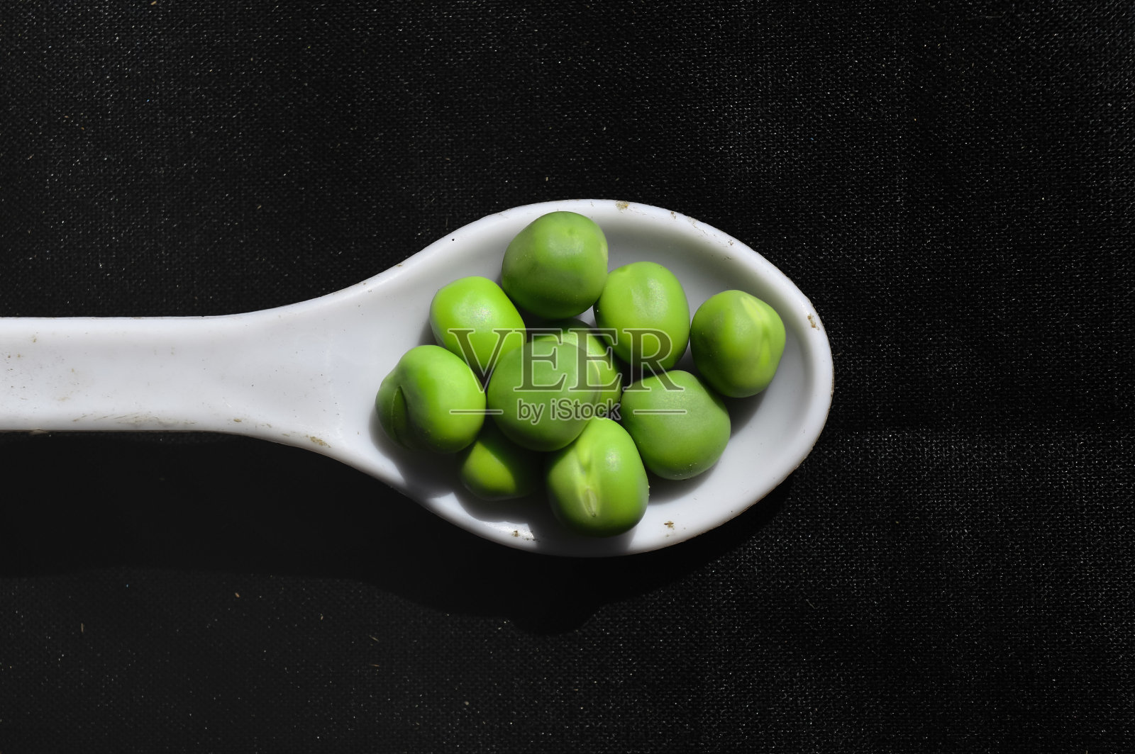 勺子在豌豆豆，白色的勺子在豌豆豆，近距离观看绿色豌豆照片摄影图片