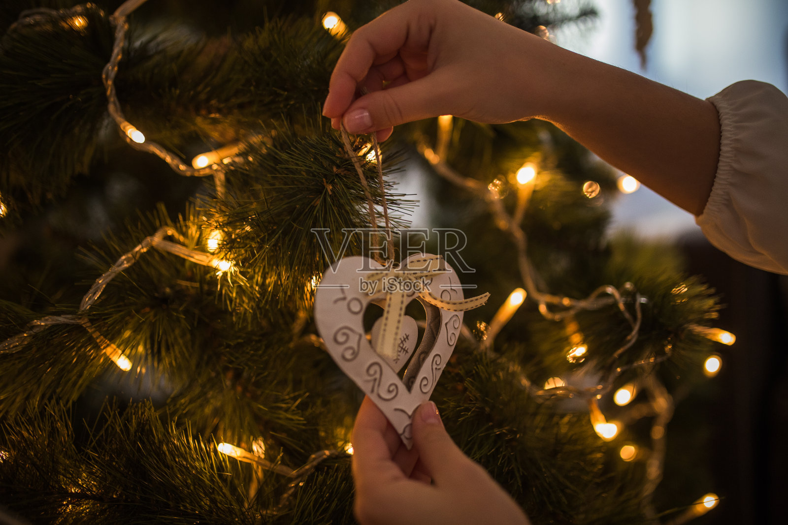 女人用手装饰圣诞树用心形的白色装饰品照片摄影图片
