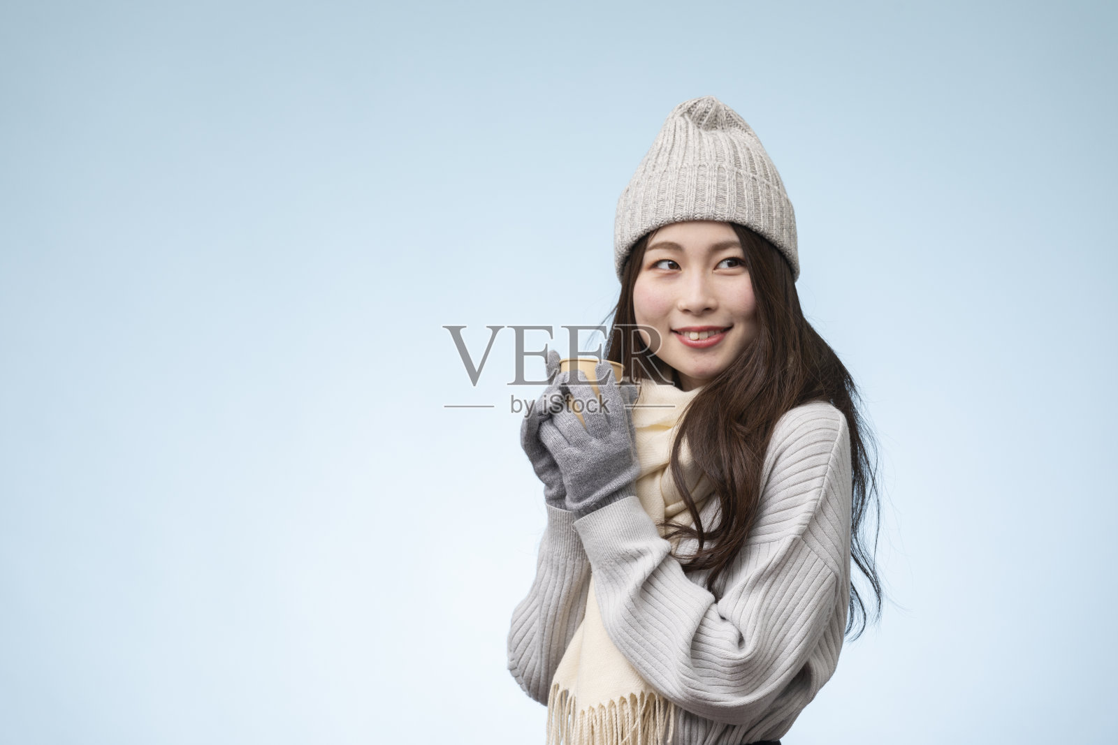 年轻女子的肖像，穿着冬装，以淡蓝色为背景照片摄影图片