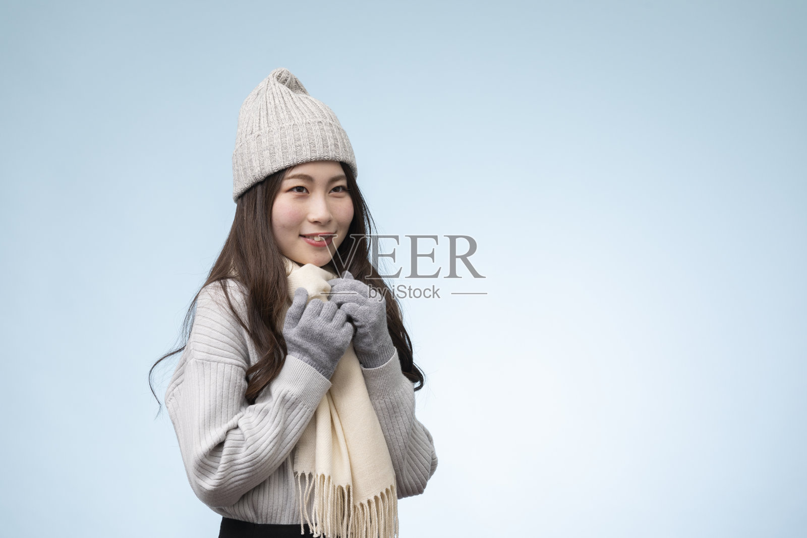 年轻女子的肖像，穿着冬装，以淡蓝色为背景照片摄影图片