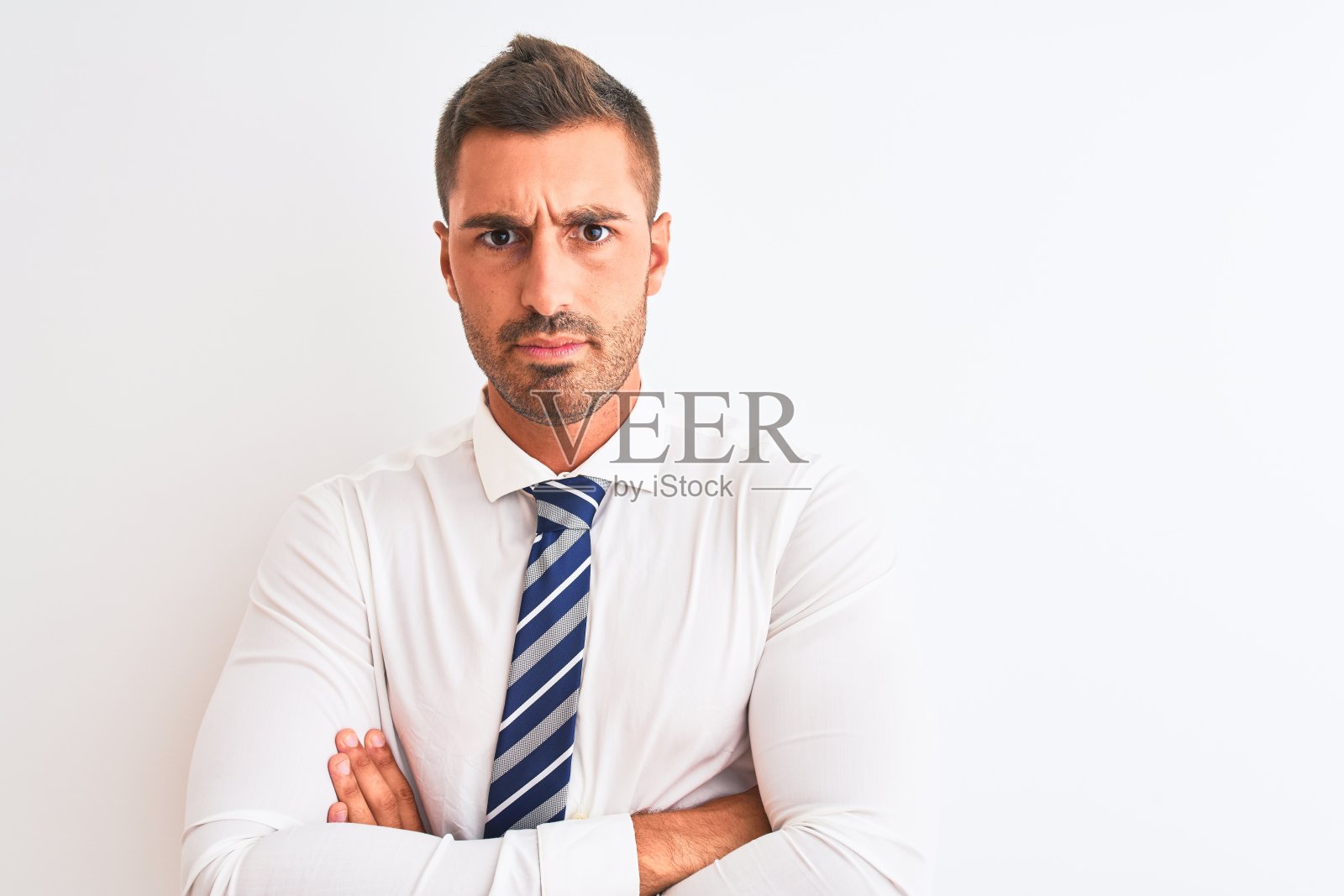 年轻英俊优雅的商人在孤立的背景怀疑和紧张，不赞成的表情与交叉的双臂。消极的人。照片摄影图片