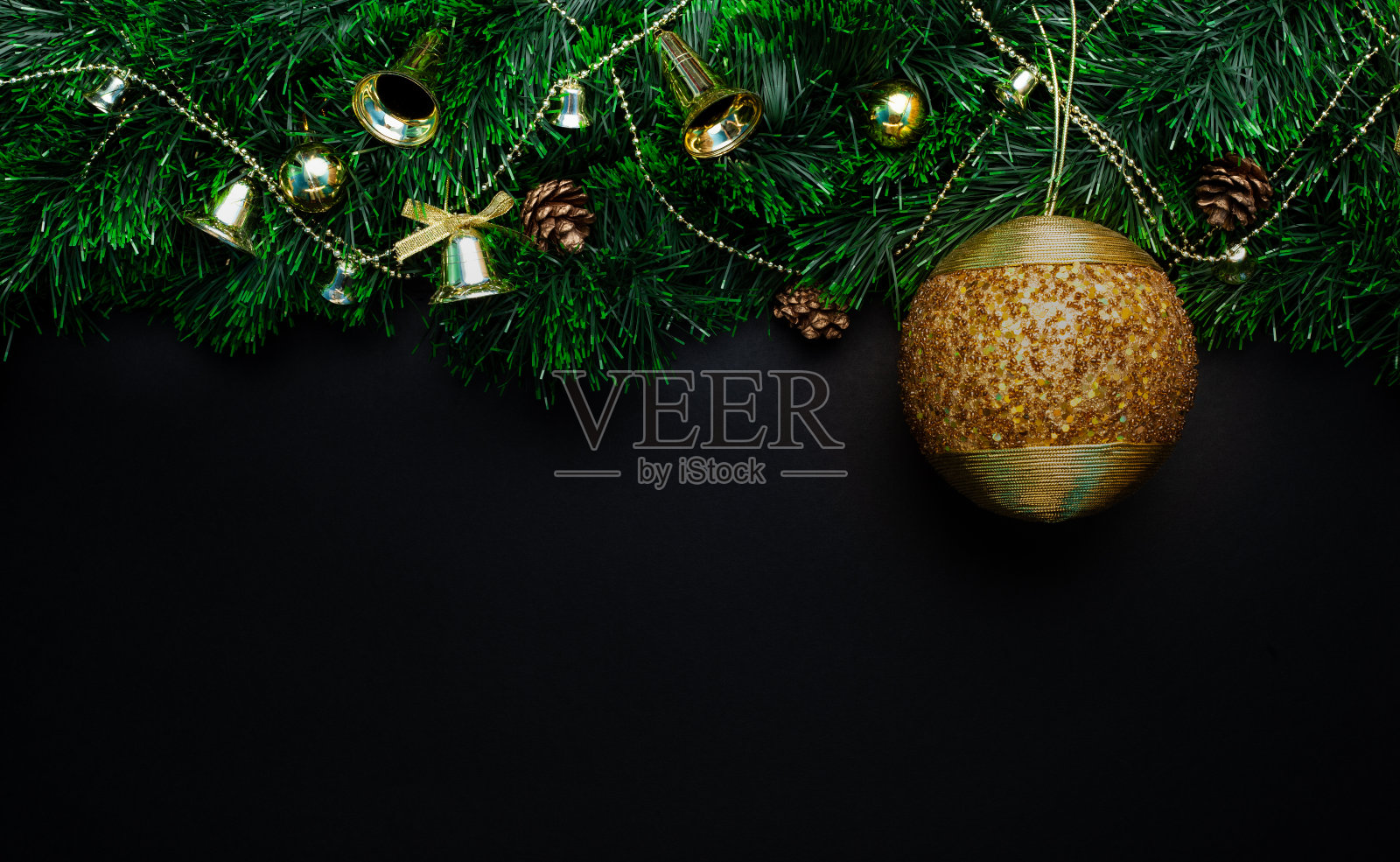 圣诞花环装饰着一个大的金球的珠子和铃铛，锥体，珠子在一个黑色的背景照片摄影图片