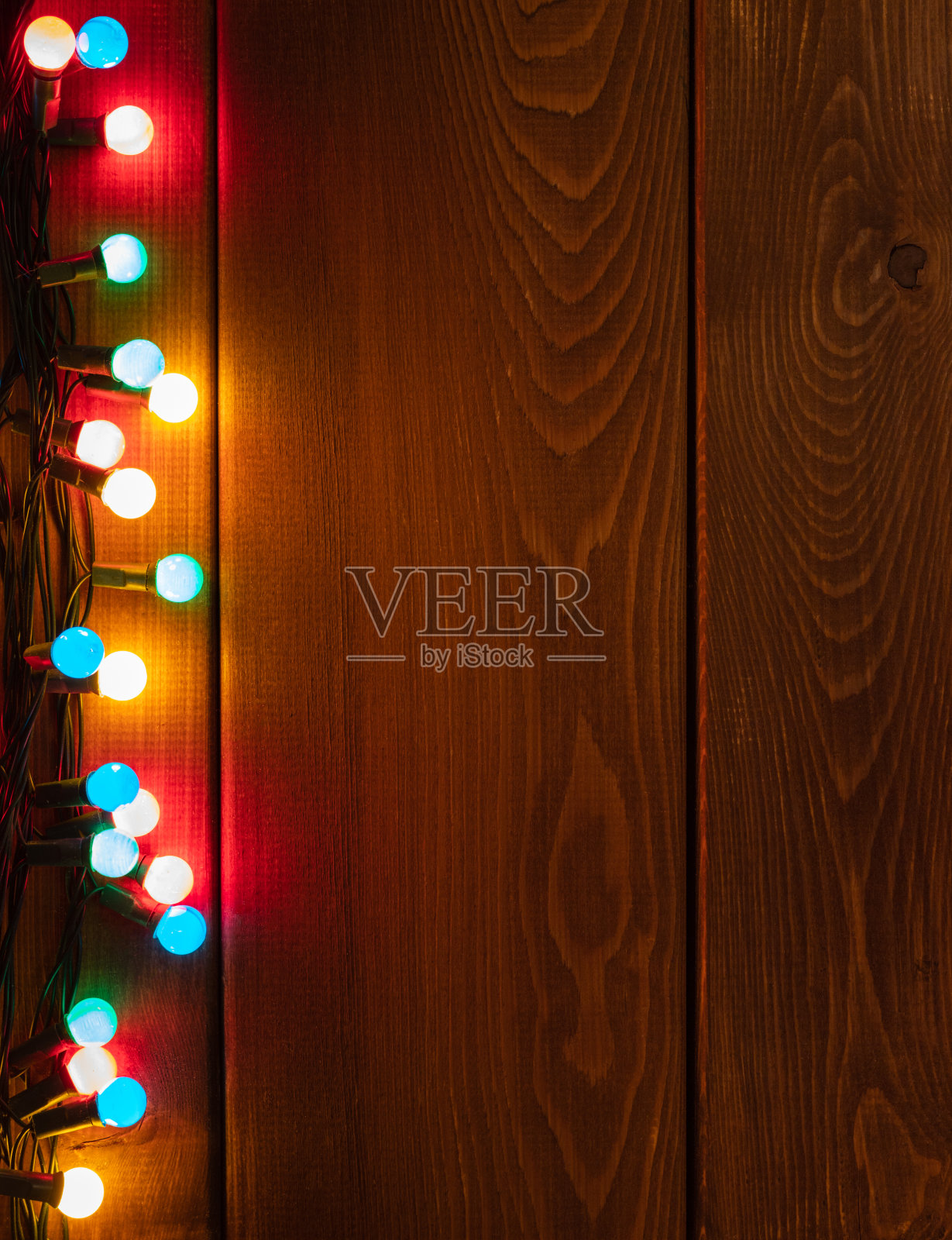 圣诞节的边界上有五颜六色的花环。深色木书桌上的圣诞背景照片摄影图片