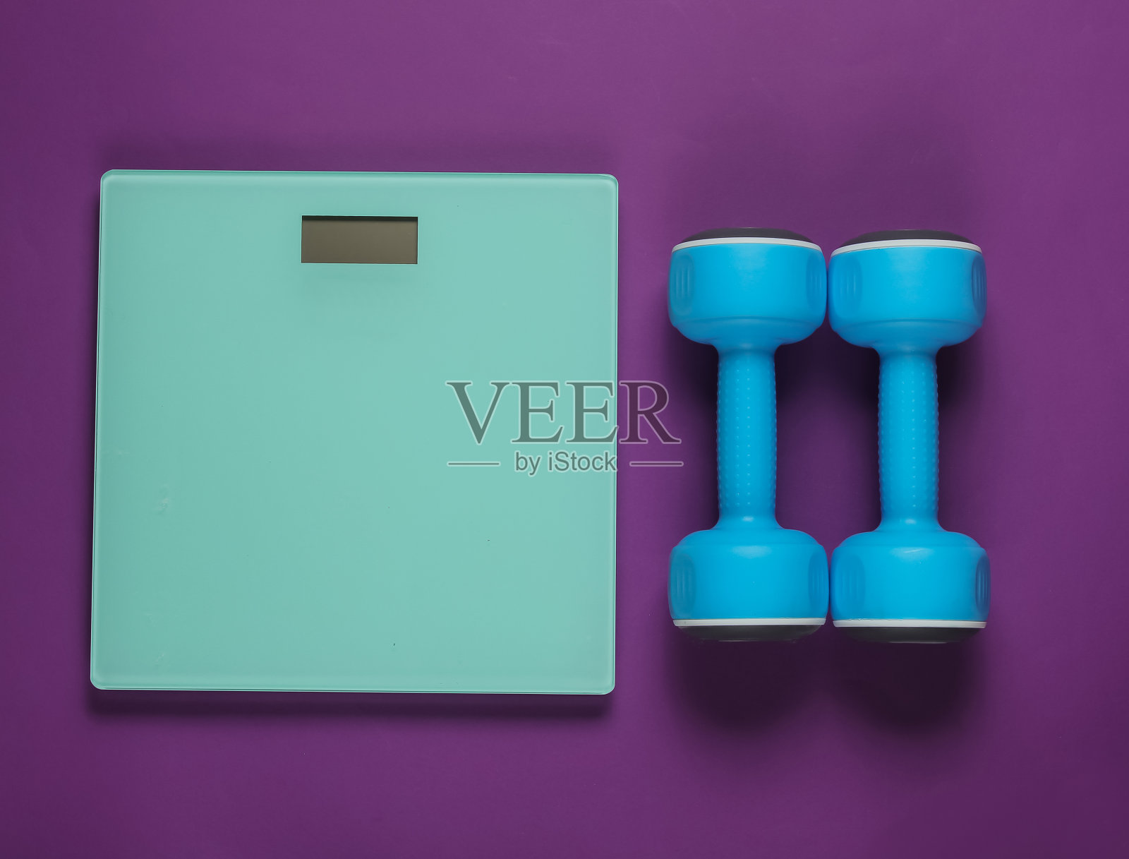 紫色背景上的地板秤和哑铃。运动理念，健身训练。影棚拍摄照片摄影图片