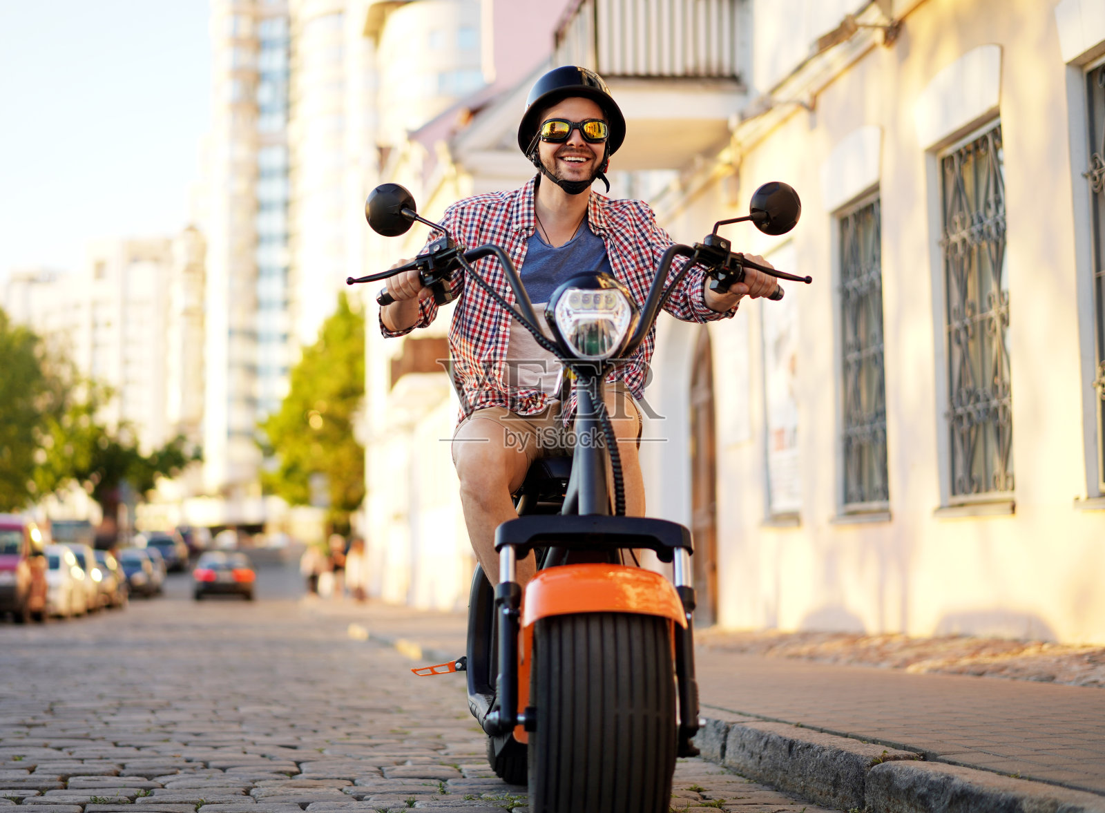 时髦的年轻人骑着橙色的摩托车在街上。照片摄影图片